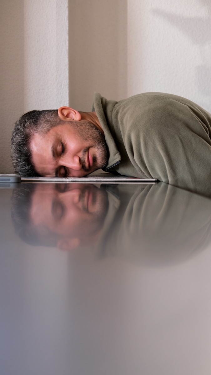Photo by Esra Afşar A man is sleeping on the floor with his head on a laptop