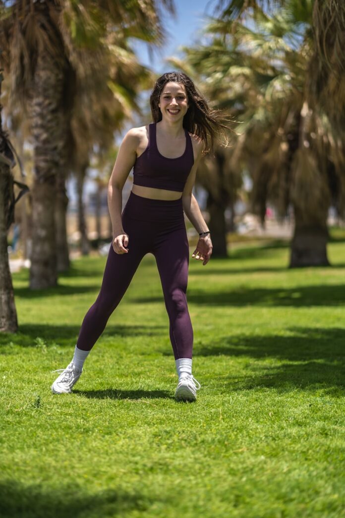 Photo by Or Hakim woman in black tank top and purple leggings running on green grass field during daytime