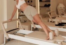 옆구리 실종 사건: 통허리를 잘록한 모래시계 라인으로 Woman does pilates on a machine in a studio.