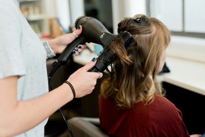 Photo by Adam Winger woman in red long sleeve shirt holding hair blower