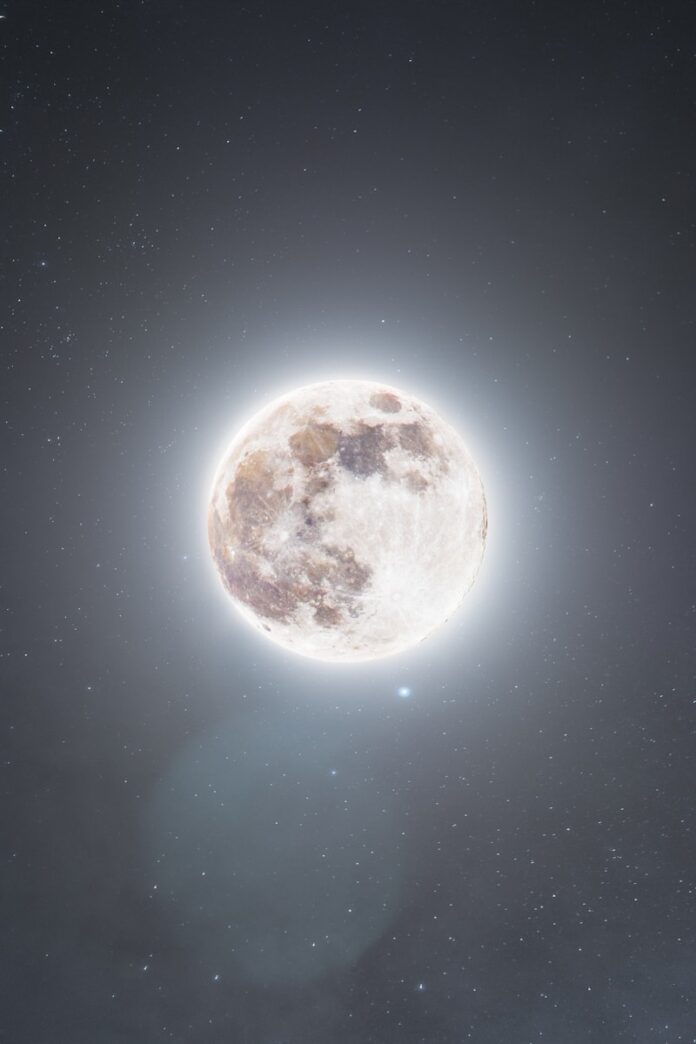 Photo by Jeremy Hynes A glowing full moon in a dark, starry night sky.