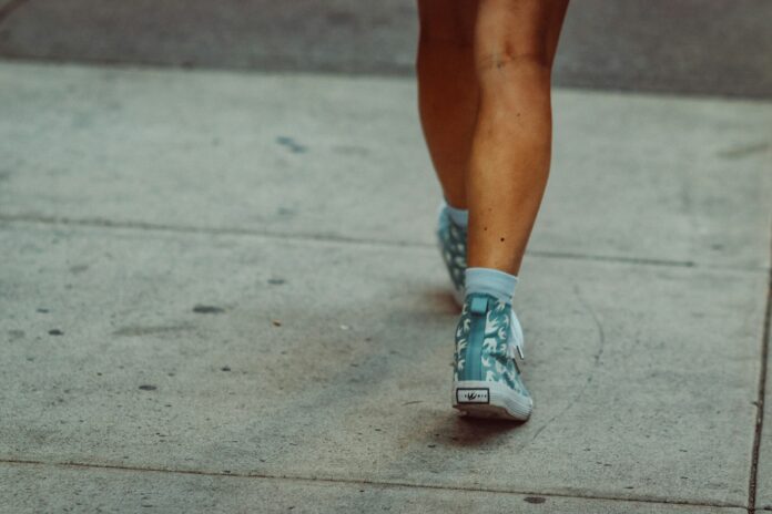 Photo by Jon Tyson Legs and feet walking on a sidewalk